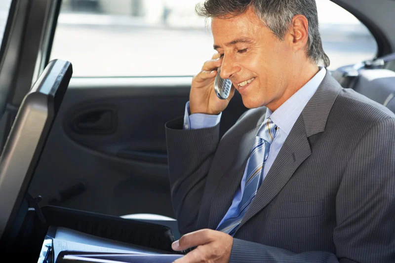 Business man talking on his cell phone, in the back seat of a car.