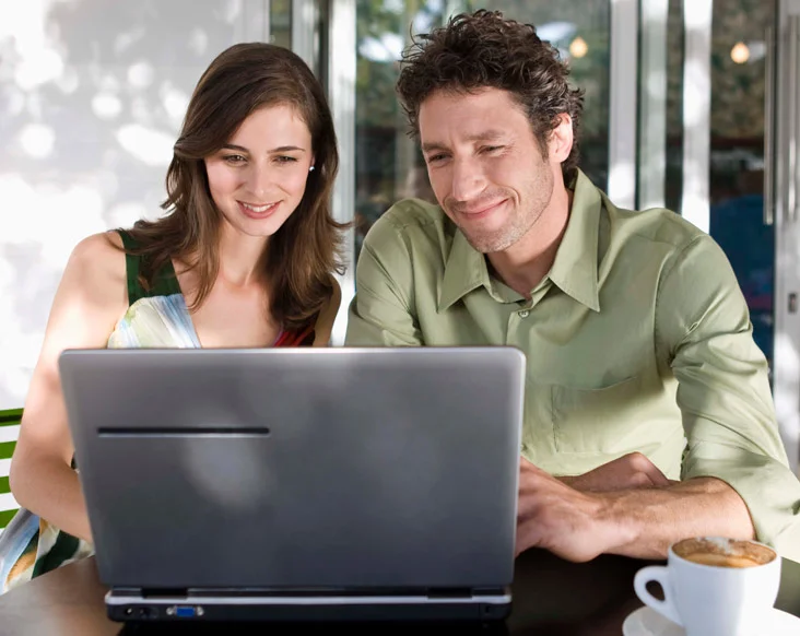 Happy man and woman looking at their laptop, paying bills online.