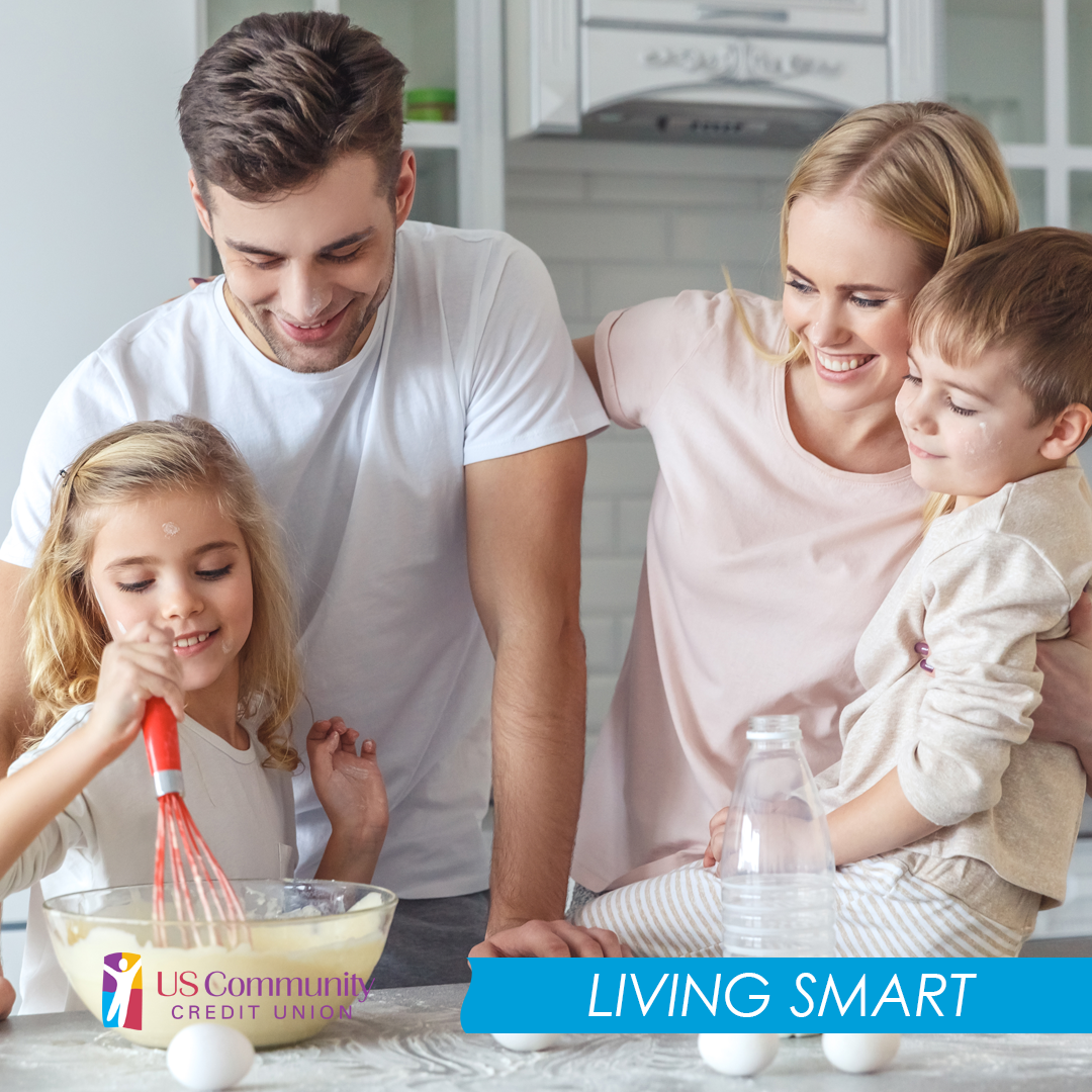 Young couple and their two kids making pancake mix with eggs and milk jug on the counter.