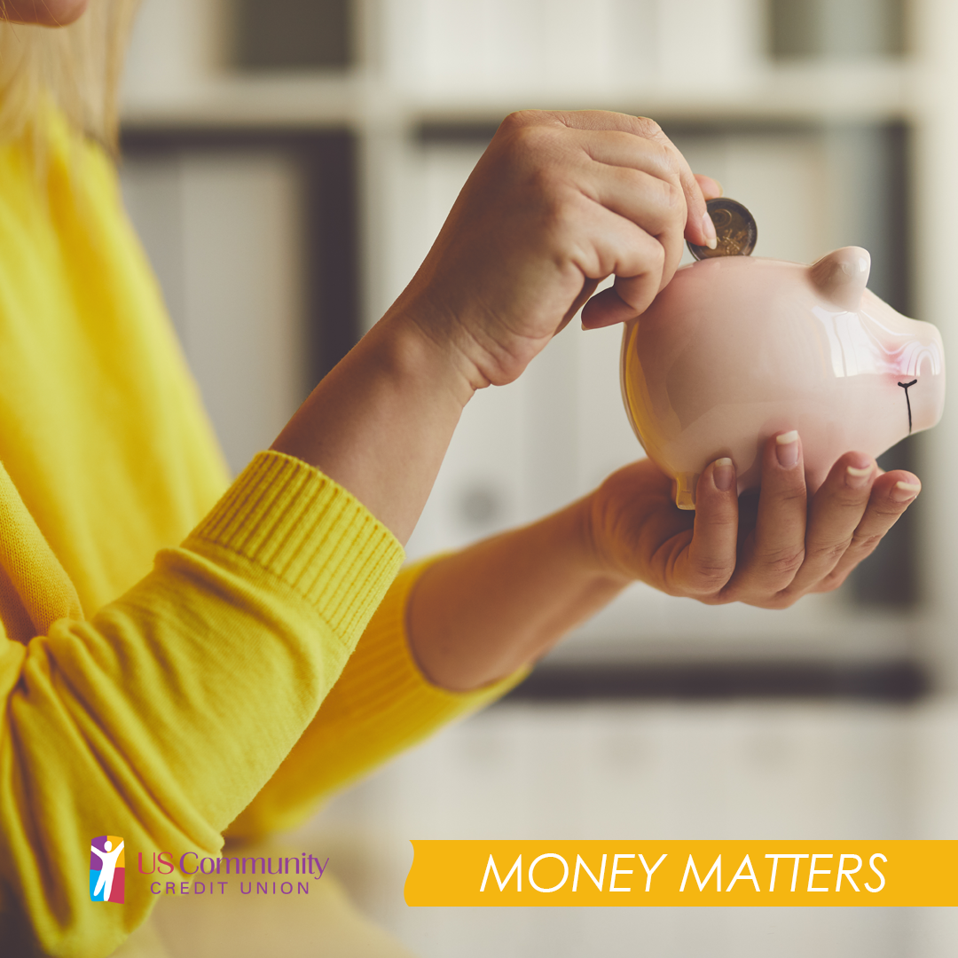 Woman in yellow blouse holding a piggy bank and putting a quarter in it.