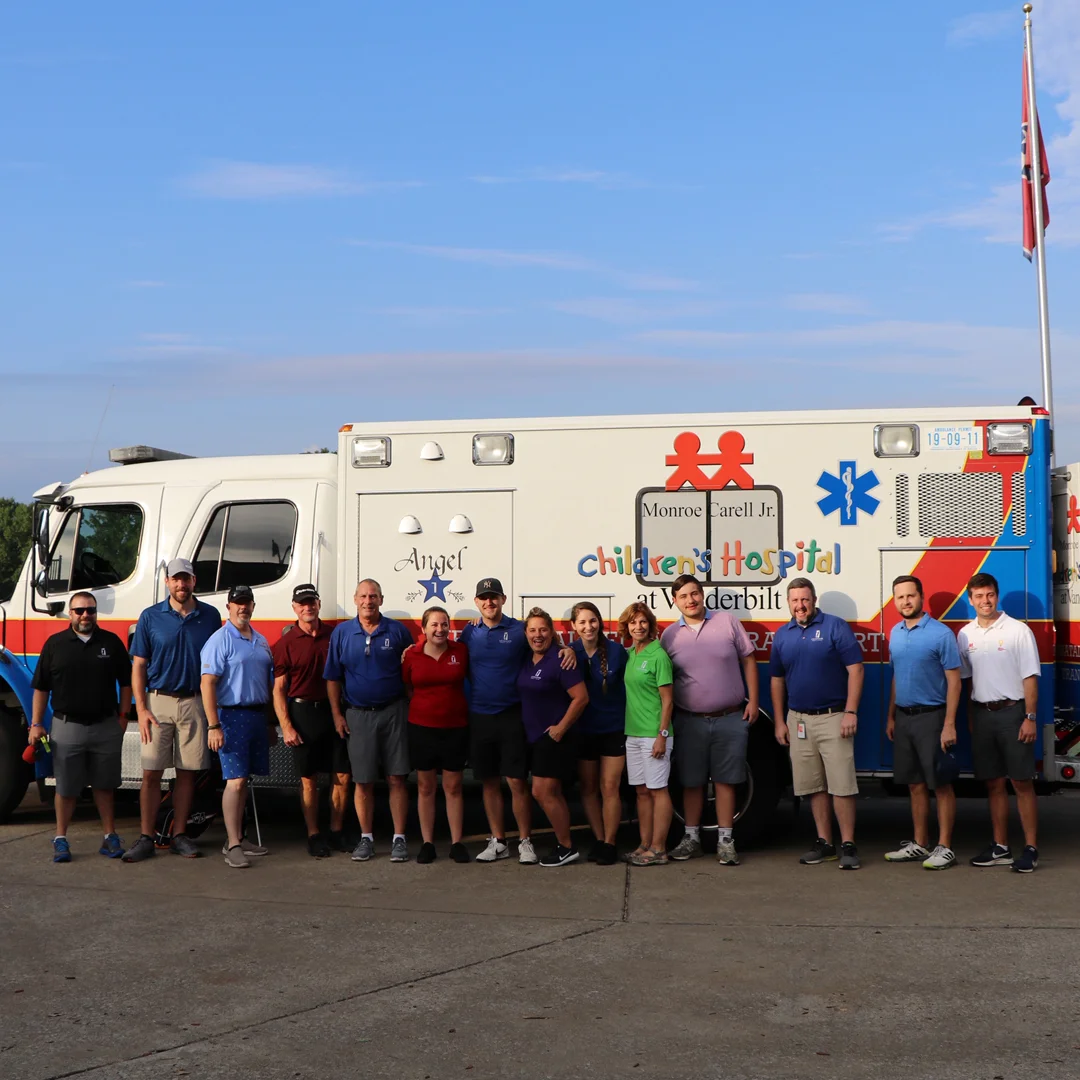 A group of people standing in front of a Vanderbilt Children’s Hospital ambulance.