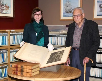 Associate Director of the Maritime Museum of British Columbia, Brittany Vis (left) with Don Hope (right) along with the donation of the 1785 Cook Journal and folio. Image provided courtesy of the Maritime Museum of British Columbia.