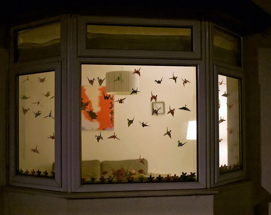Photo demonstrates folded origami on glass.