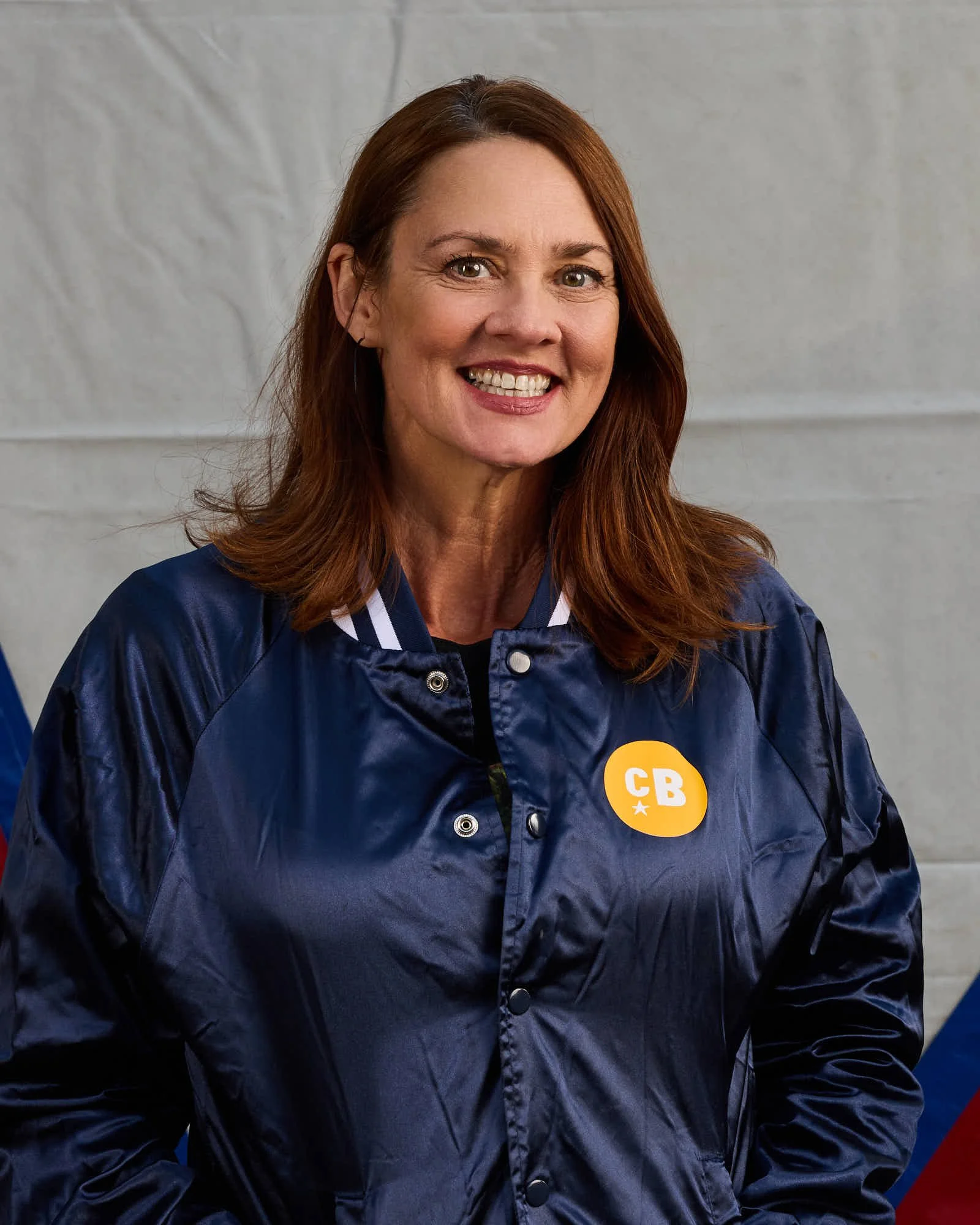 Keyboardist Katy Stephan, stands with shoulder-length brown hair smiling while holding an accordion.