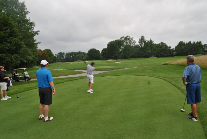 Mike hits his drive on the fourth hole as Bob, Doug and Brian watch.
