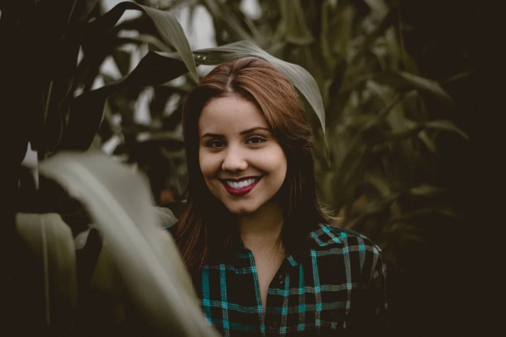 Trauma-counselling-for-Complex-Trauma-and-PTSD-in-Melbourne-with-Melburne Psychotherapist-Amanda-Robins-Young-girl-in-plaid-shirt-surrounded-by-foliage-smiling happily.