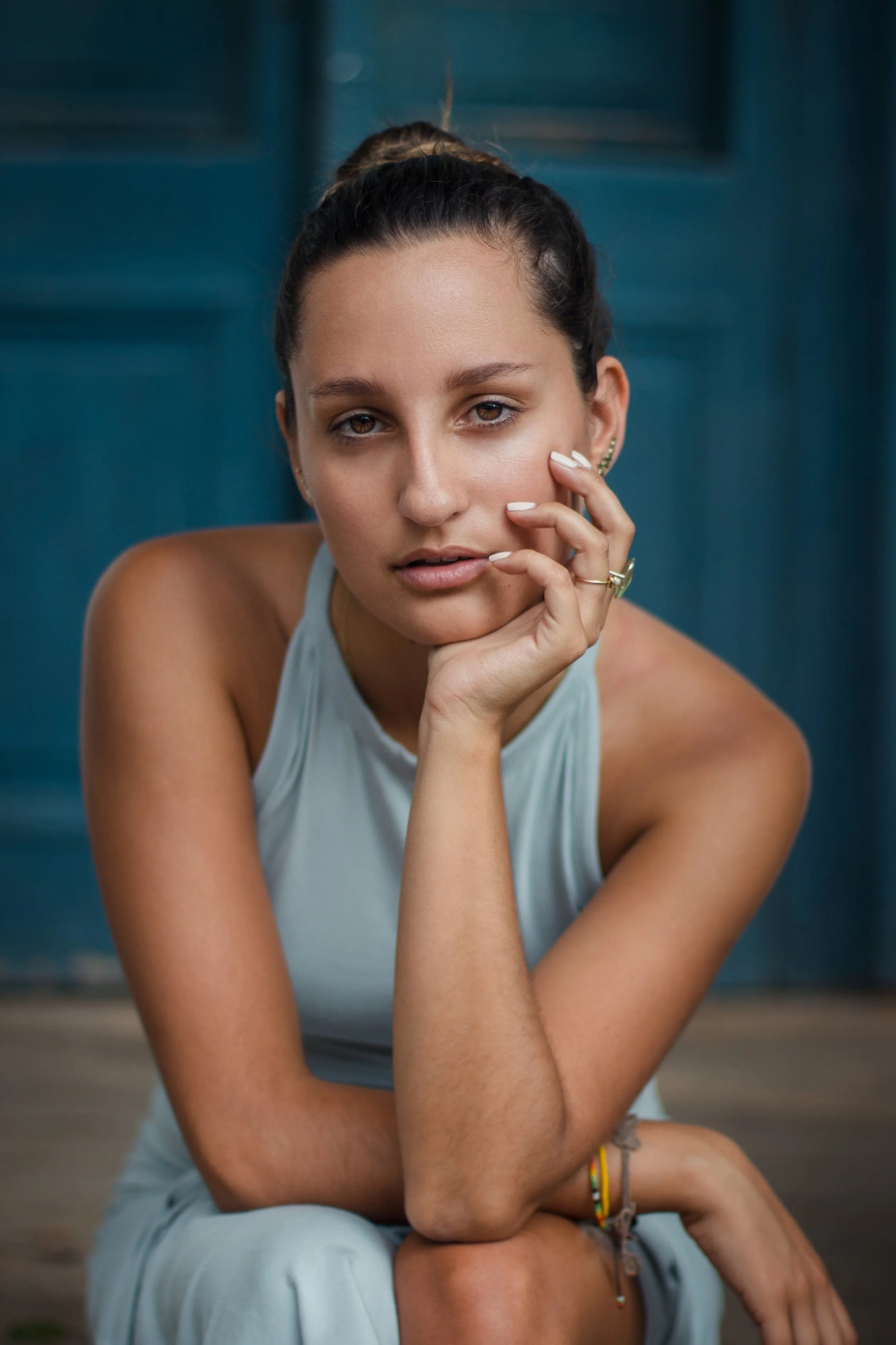 Girl-in-blue-sleeveless-top-leaning-on-elbow-looking-into-camera.