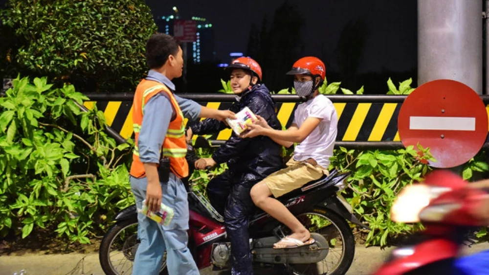 Hai cha con được giúp đỡ trong trời mưa - Ảnh: HỮU THUẬN