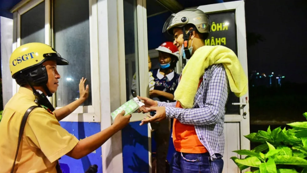 Thượng úy Trần Tuấn Anh thuộc đội CSGT Bến Thành tặng áo mưa cho người dân - Ảnh: HỮU THUẬN