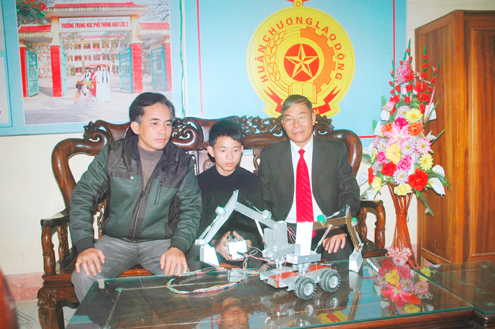 Học sinh Trần Văn Phát (giữa) đang thuyết trình về nguyên lý hoạt động của máy xúc hai tay.