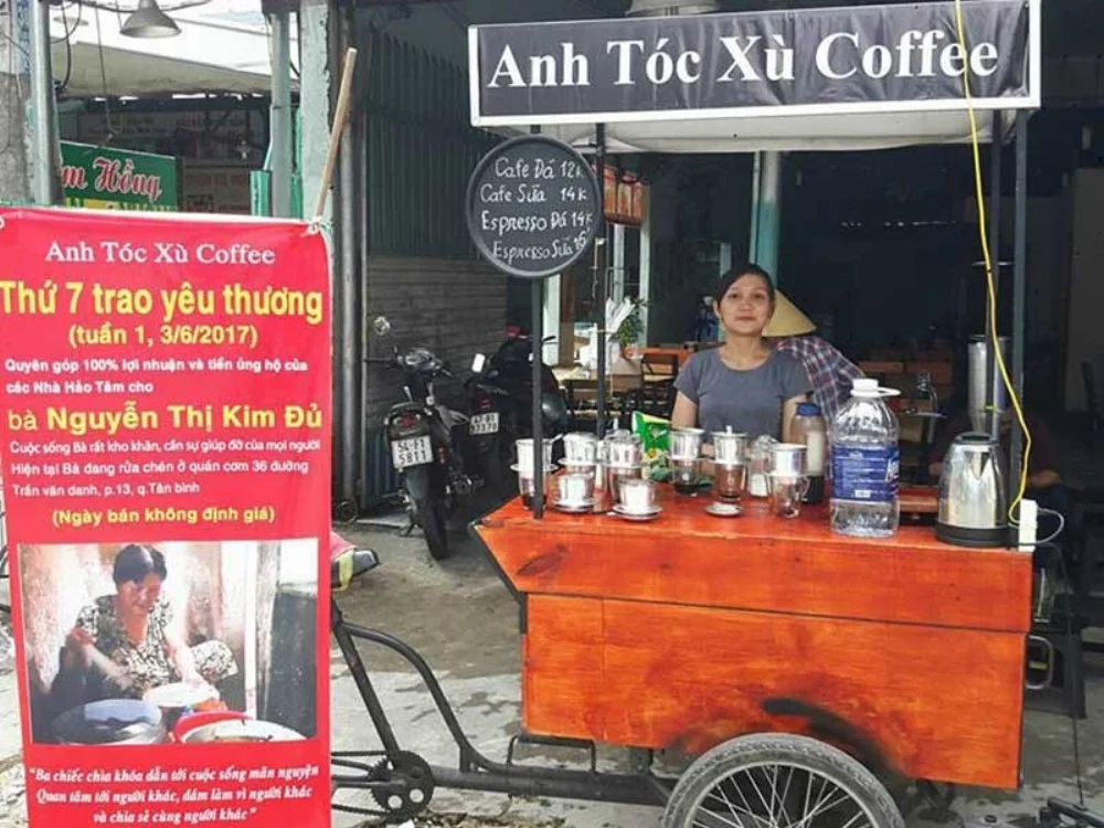 Quầy cà phê và tấm bảng “Thứ Bảy trao yêu thương”, kêu gọi hỗ trợ cho bà Đủ. Ảnh: NQ