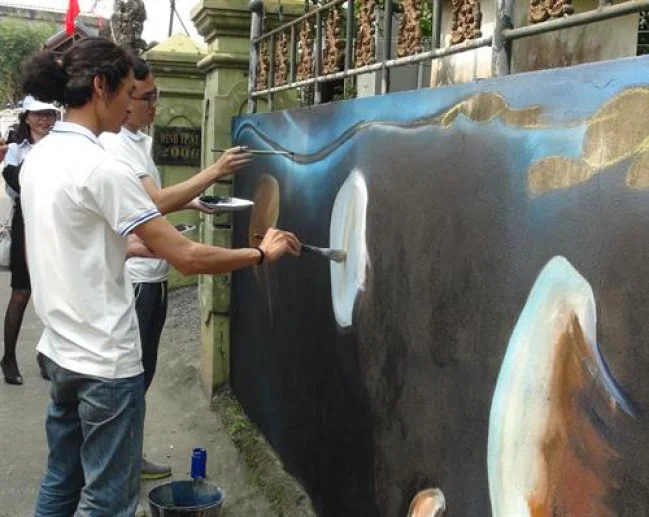 Các họa sĩ vẽ tranh 3D đang miệt mài hoàn thành các tác phẩm của mình lên tường. Ảnh: Đức Thọ - TTXVN