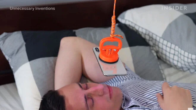 Thiết bị này có tên là iDangle. Nó thực chất là 1 sợi dây dài với 1 đầu gắn vào trần nhà, đầu còn lại gắn vào chiếc điện thoại của người dùng. Và thế là họ có thể thoải mái nằm thư giãn trên giường, lướt web hay xem phim mà không sợ bị mỏi tay nữa.