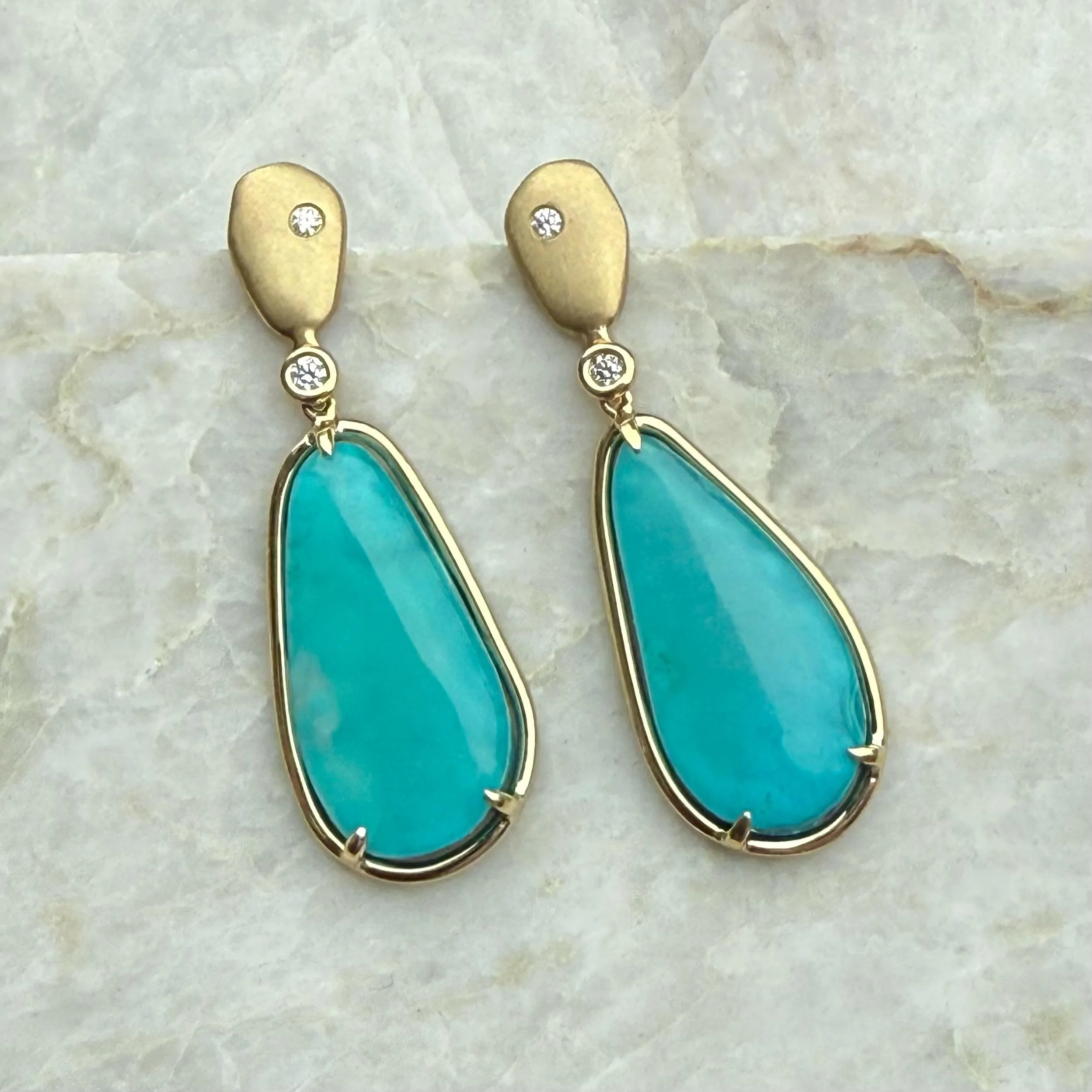 Summer is here with vibrant glowing blue!

These vivid blue stones are gem silica, chrysocolla. They are from Arizona and their blue color comes from copper. They have a glowing translucency and contrast beautifully with the 18k yellow gold.
