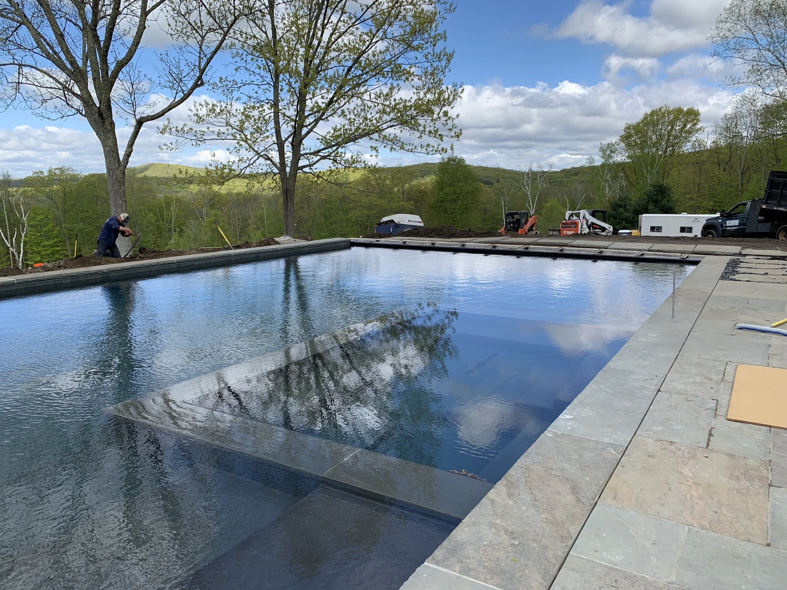 The pool features a large integrated spa flanked by gradual tiered platforms.