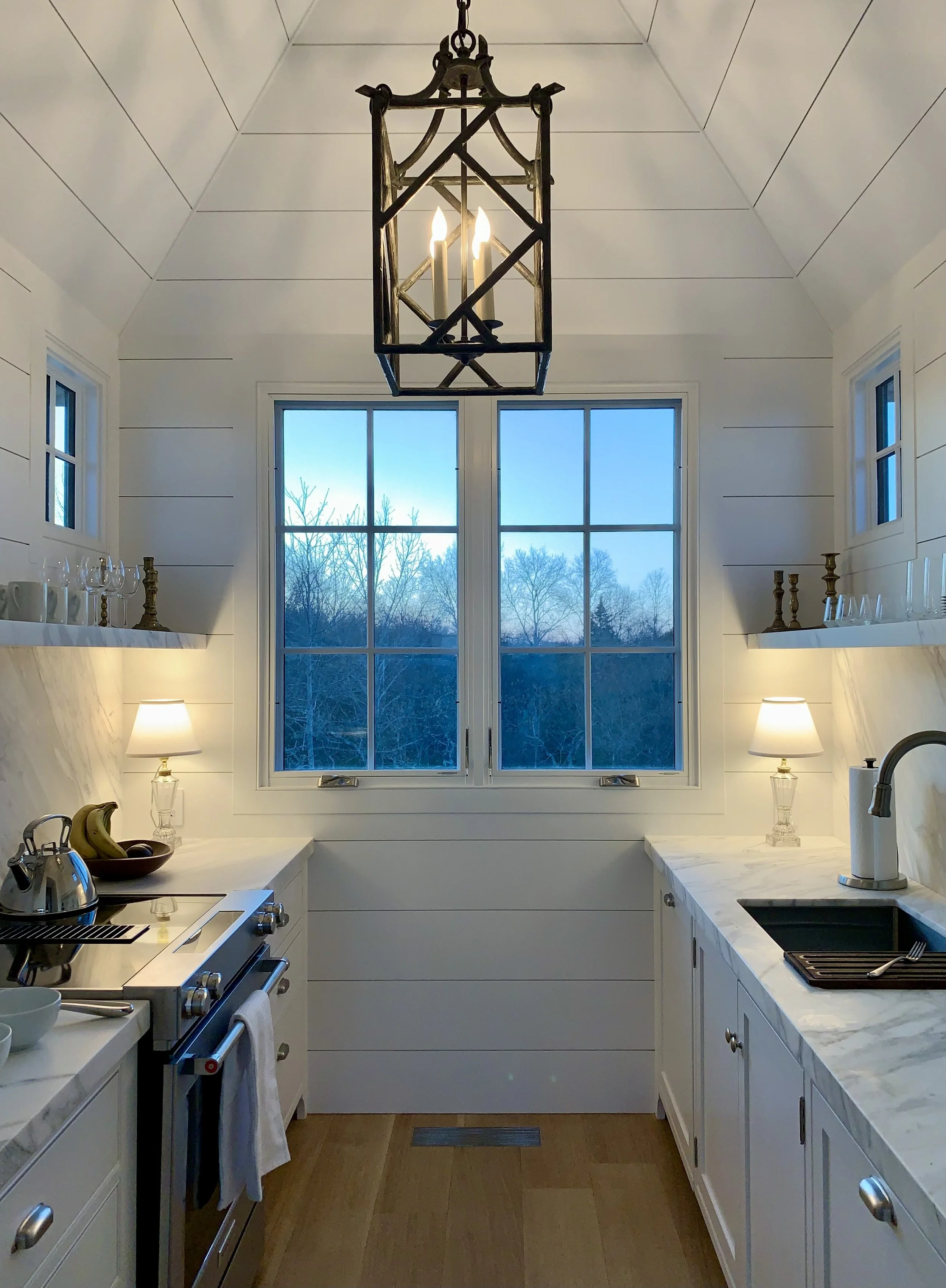 The kitchen features Calacatta marble counters and shelves and a pyramidal ceiling.
