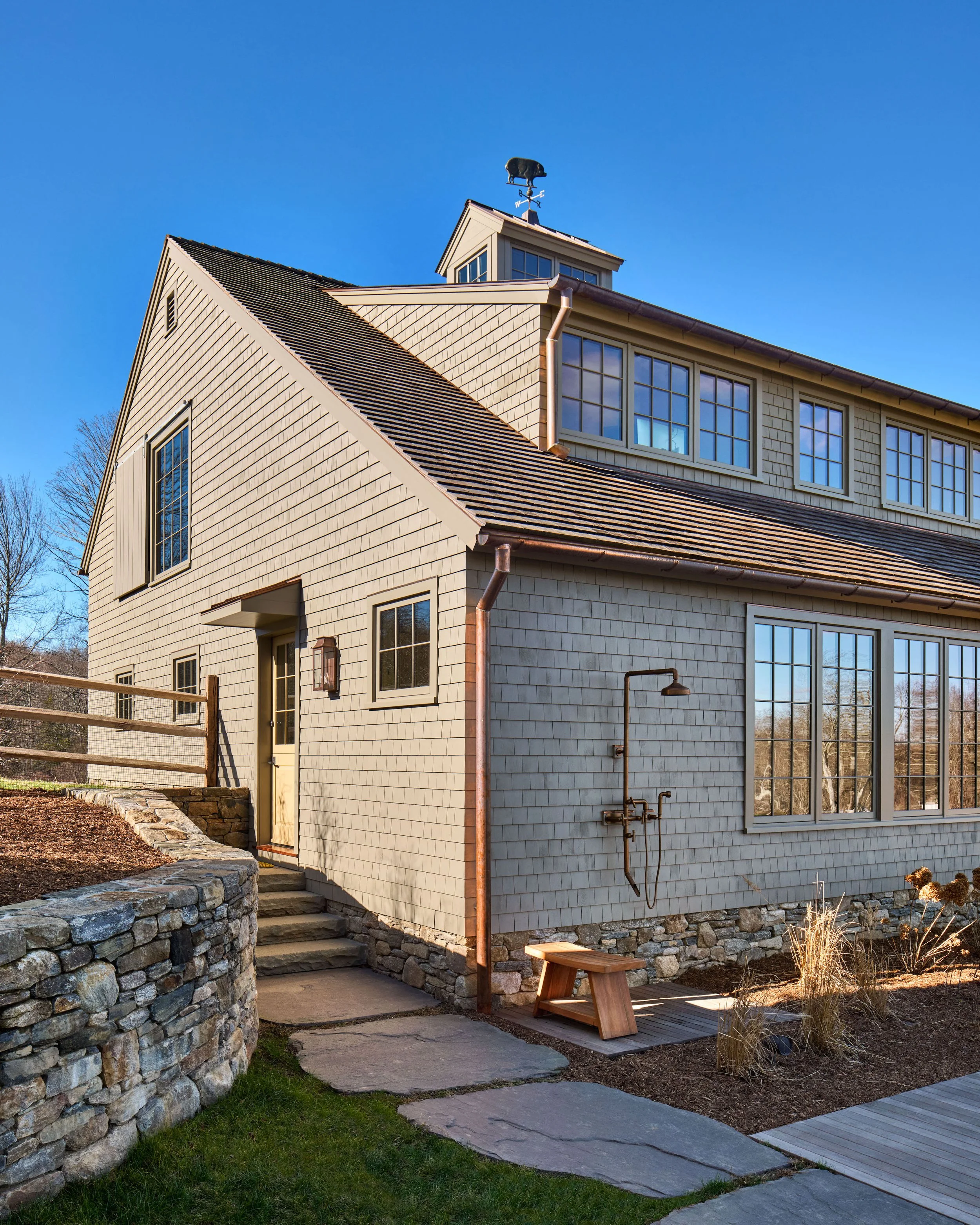  A curved fieldstone wall and giant bluestone pavers lead to the south Carriage House entrance.&nbsp; A rustic copper outdoor shower serves the nearby swimming pool. 