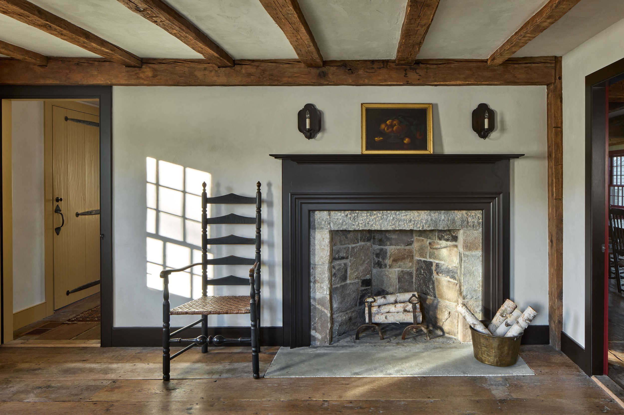  The three fireplaces of the saltbox’s center chimney are reconstructed utilizing stone salvaged from the original.&nbsp;&nbsp; Walls throughout the antique and new sections of the home are of unpainted rough plaster. 