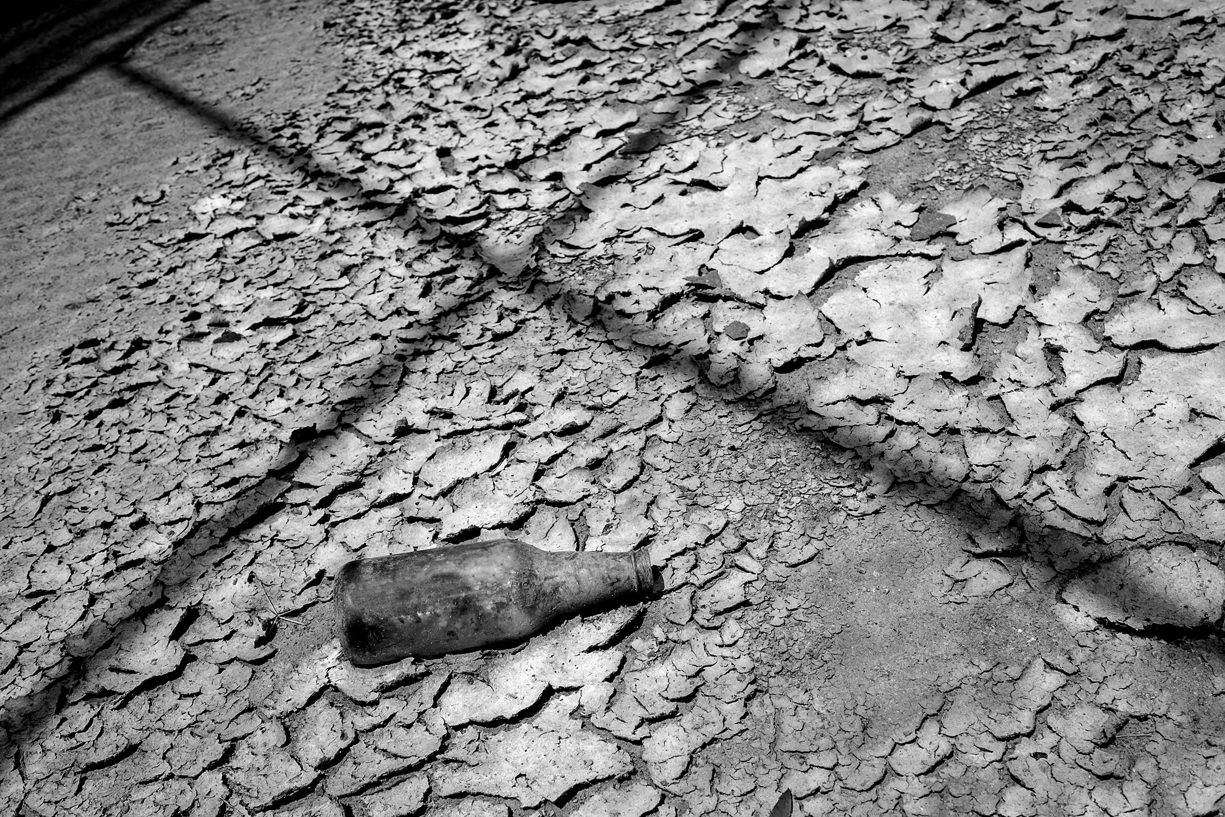 Bottle-On-Cracked-Mud-Surface-On-Ballfield-W-Shadows-Near-Oak-Grove-Park-Grapevine-BW_4092.jpg