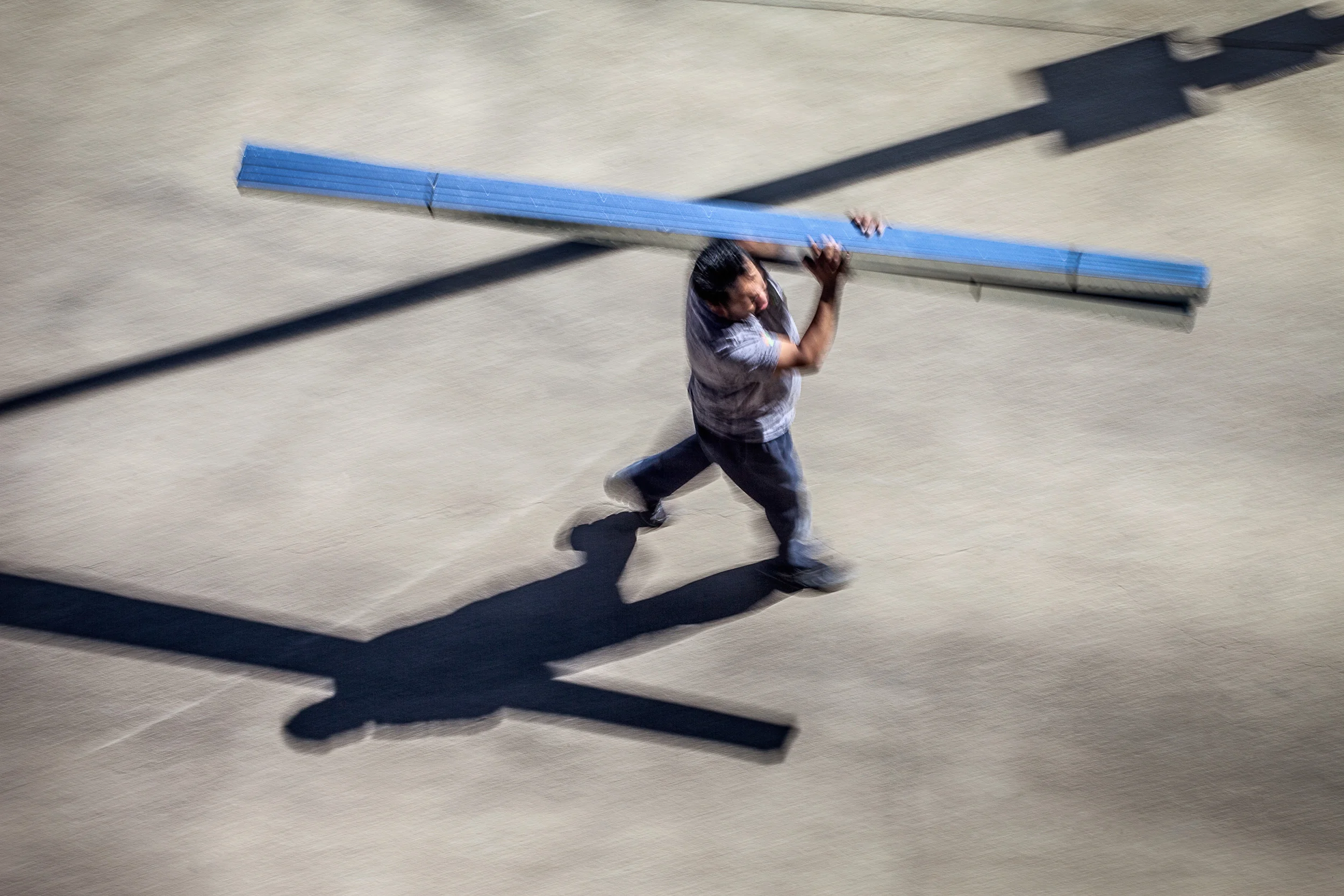 Man-Carrying-Long-Metal-Studs-On-His-Shoulder-W-Shadow-From-Studio-Window_91303.jpg
