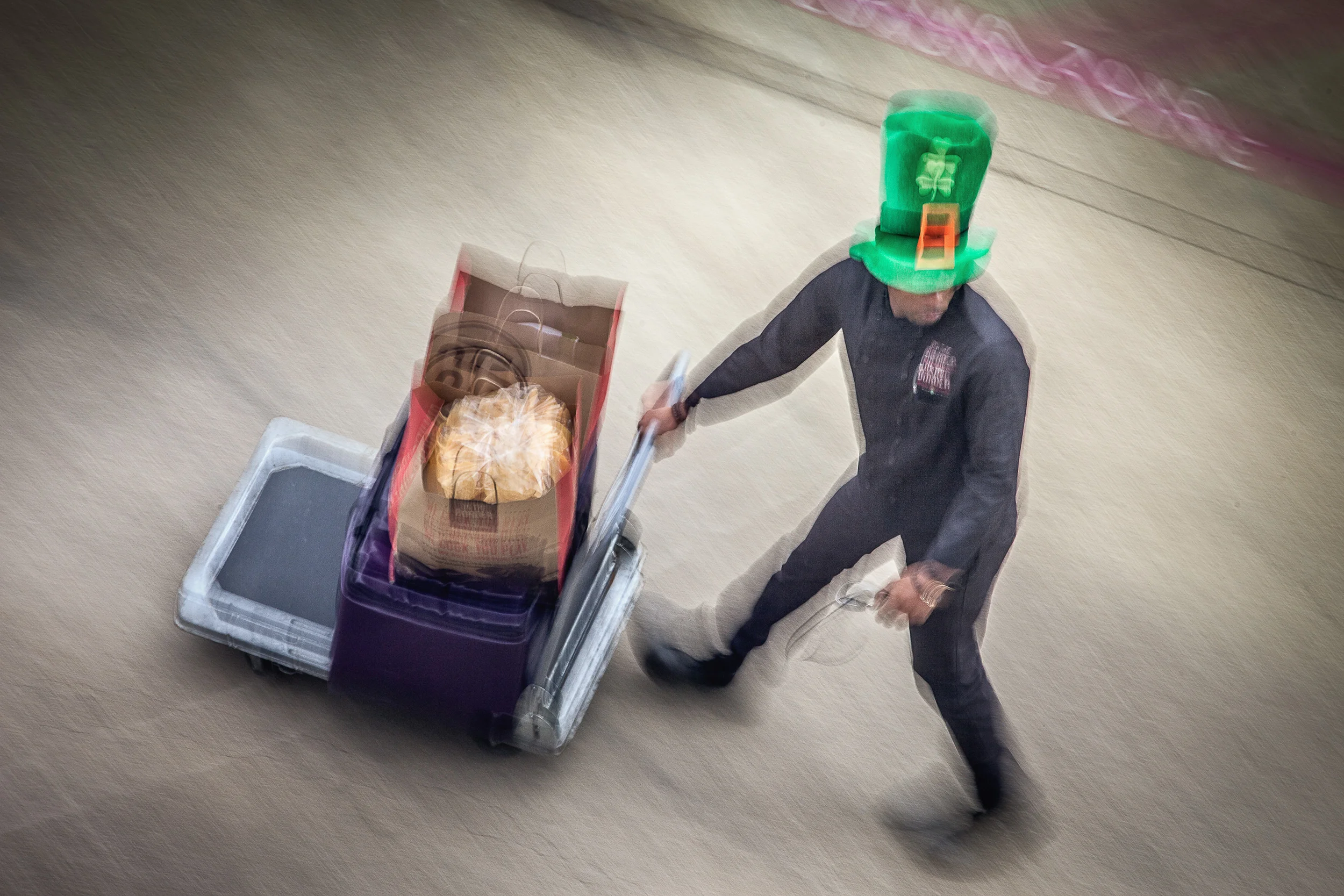Man-In-Leprechaun-Hat-W-Cart-Of-Food-Bags-Going-Behind-Building-From-Studio-Window_87341.jpg