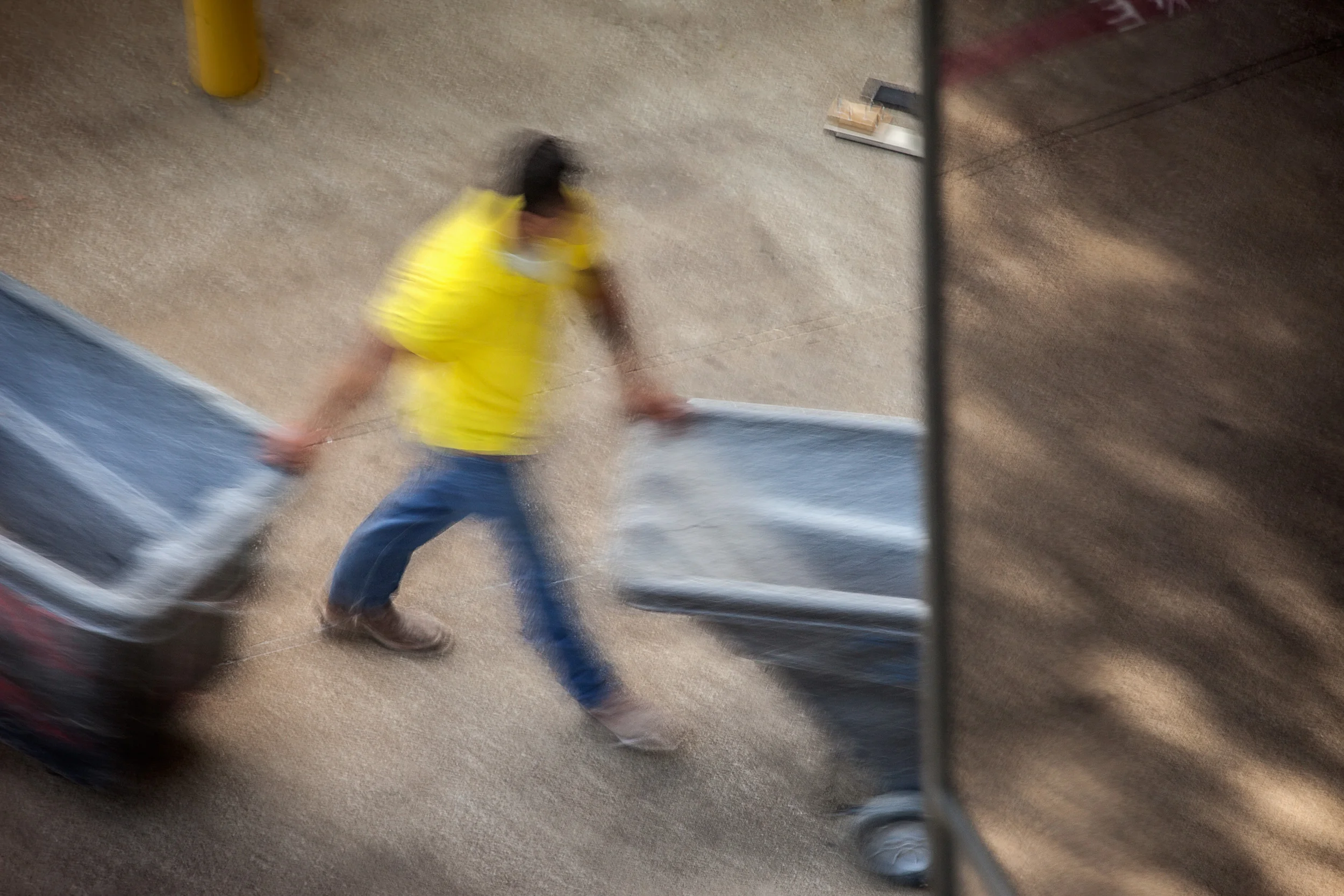 Man-In-Yellow-Shirt-Pulling-Empty-Bin-Behind-Building-From-Studio-Window_104757.jpg
