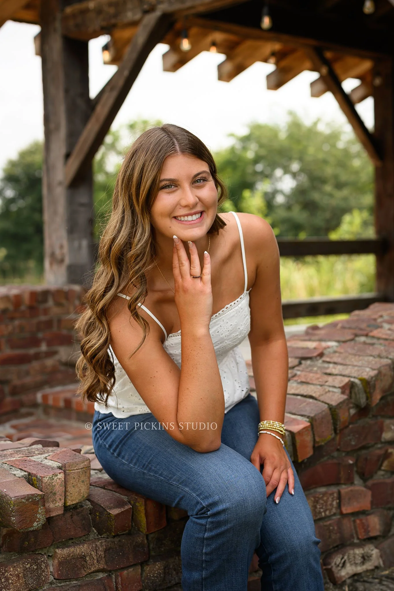 Zionsville, Indiana Country Senior Portrait Photography at Traders Point Creamery with class of 2027 senior girl posing in white dress and red western boots at dairy barn by Sweet Pickins Studio senior photographer Amanda Wilson ©
