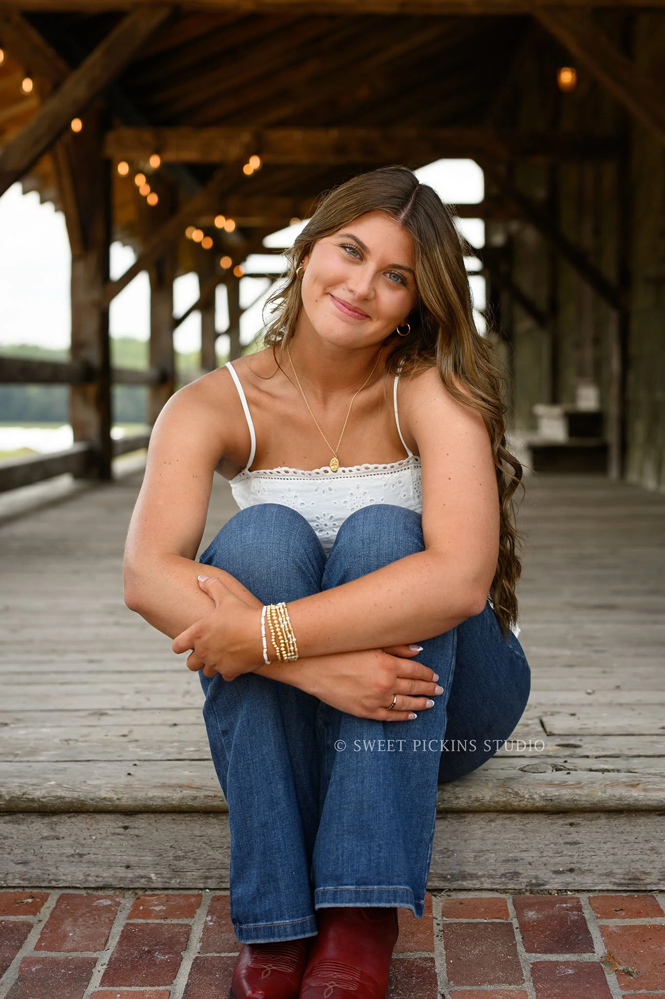 Zionsville, Indiana Senior Portrait Photography at Traders Point Creamery with class of 2027 senior girl wearing denim jeans and red western boots at barn by Sweet Pickins Studio senior photographer Amanda Wilson ©
