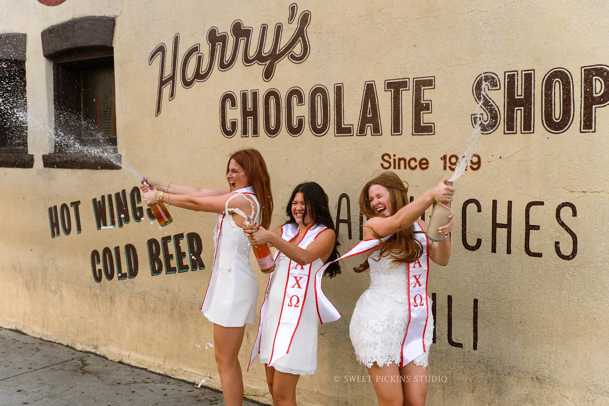 Purdue Graduation Photography for Sorority Sisters champagne pop at Harry’s Chocolate Shop in West Lafayette, Indiana by Sweet Pickins Studio photographer Amanda Wilson  © 2026