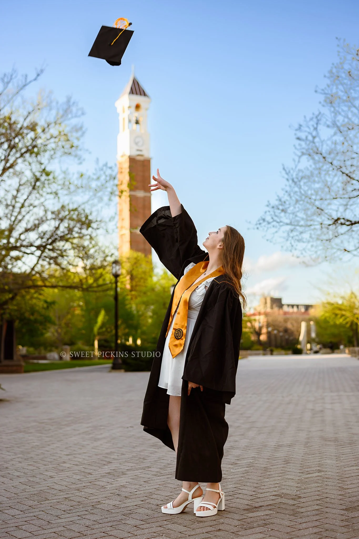 Emily | Purdue University Graduation Portraits in West Lafayette, Indiana at Bell Tower tossing cap in Spring by Sweet Pickins Studio senior photographer Amanda Wilson ©