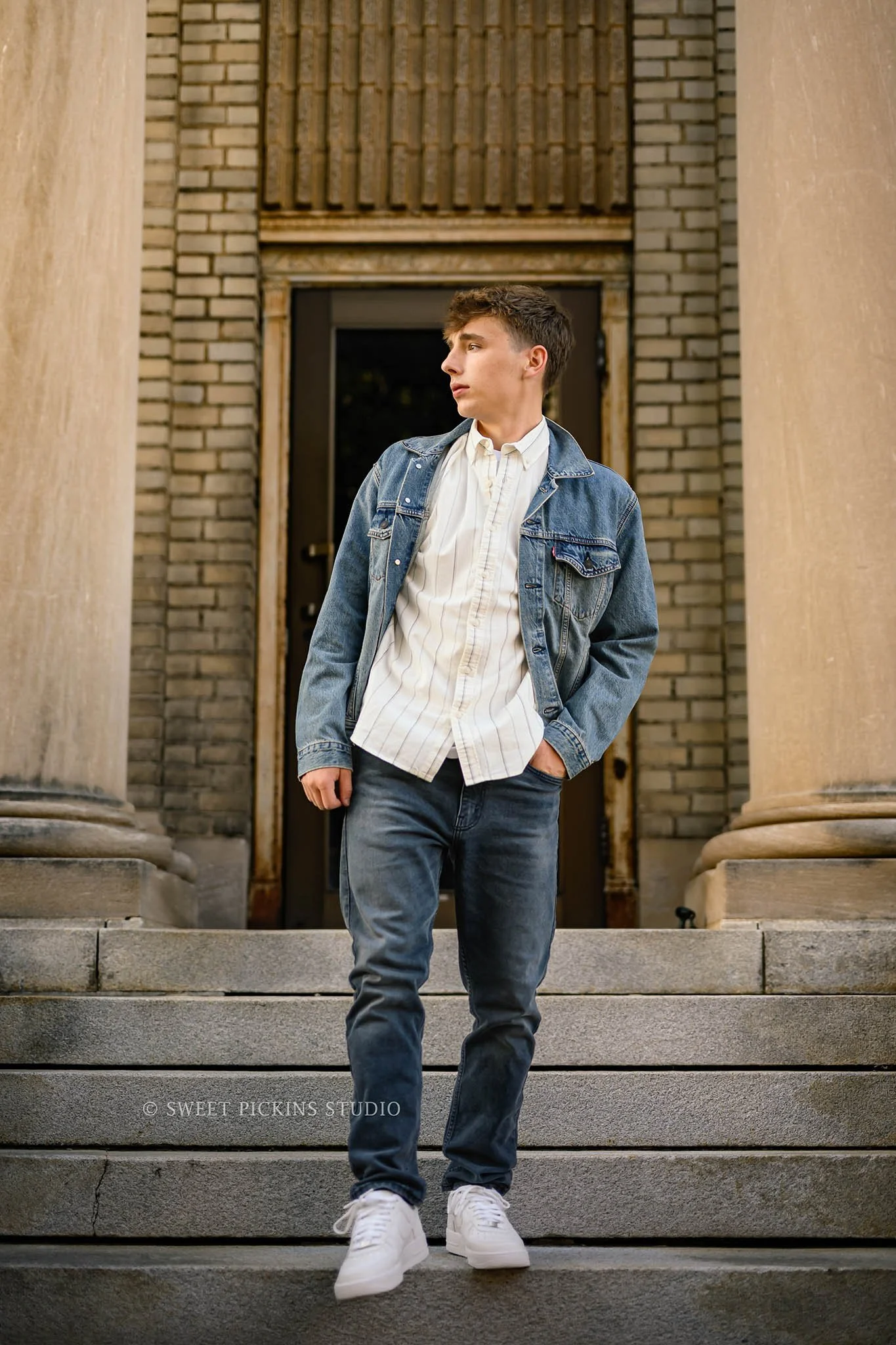 Huntington, Indiana Fall Senior Pictures for Huntington North Class of 2027 Senior Guy BOSTAN walking down concrete steps in denim jean jacket in urban downtown by Sweet Pickins Studio senior photographer Amanda Wilson ©