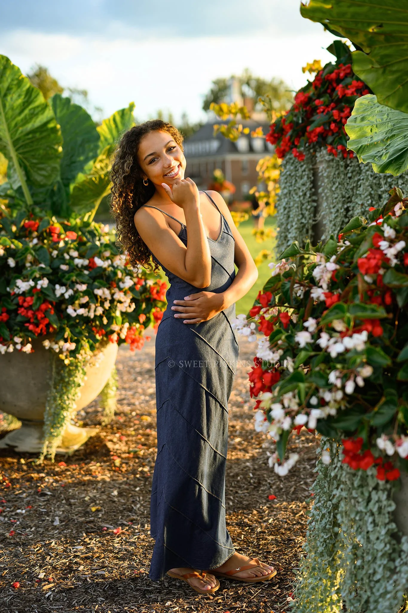 Madeline | Indiana Floral Senior Girl Photography posing by flowers for Speedway High School Class of 2027 wearing denim maxi dress by Sweet Pickins Studio senior photographer Amanda Wilson ©