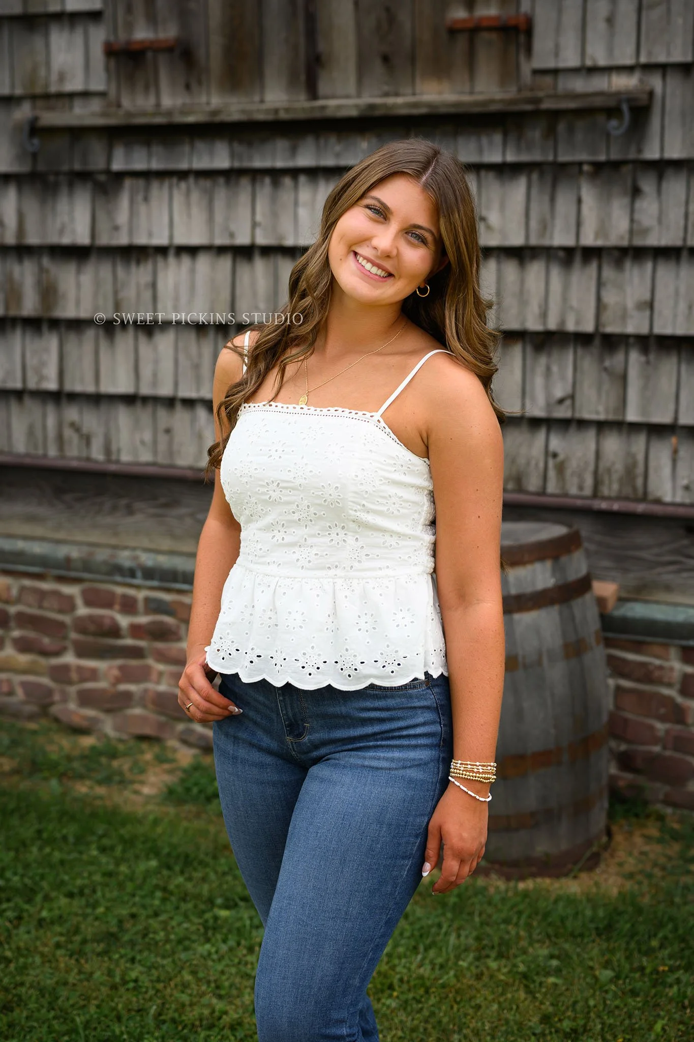 Zionsville, Indiana Country Senior Portrait Photography at Traders Point Creamery with class of 2027 senior girl posing in white dress and red western boots at dairy barn by Sweet Pickins Studio senior photographer Amanda Wilson ©