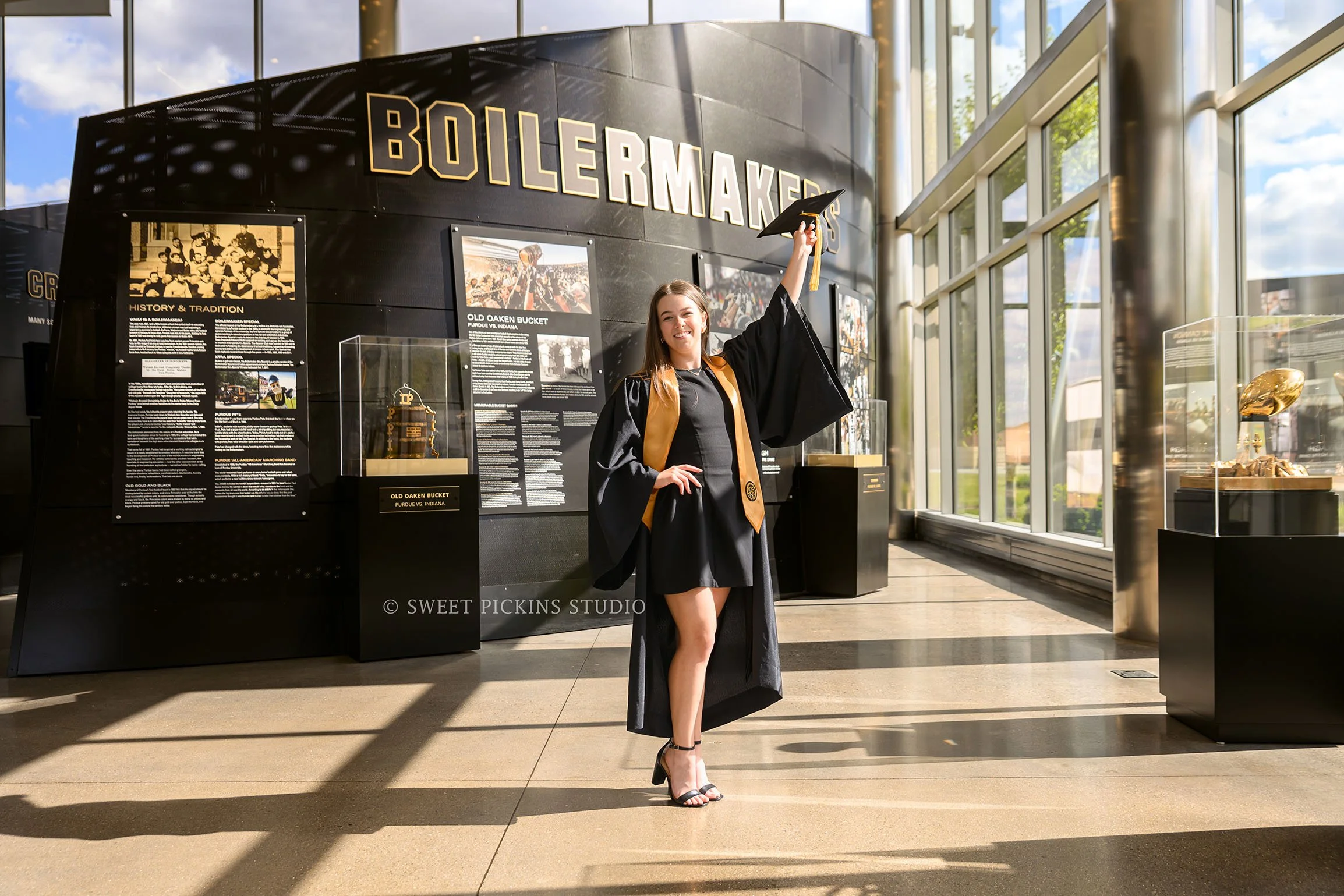 Ashelyn’s Purdue University Graduation Portrait Photography at Boilermaker Blake Lobby with trophies in West Lafayette, Indiana by Sweet Pickins Studio senior photographer Amanda Wilson © 2026