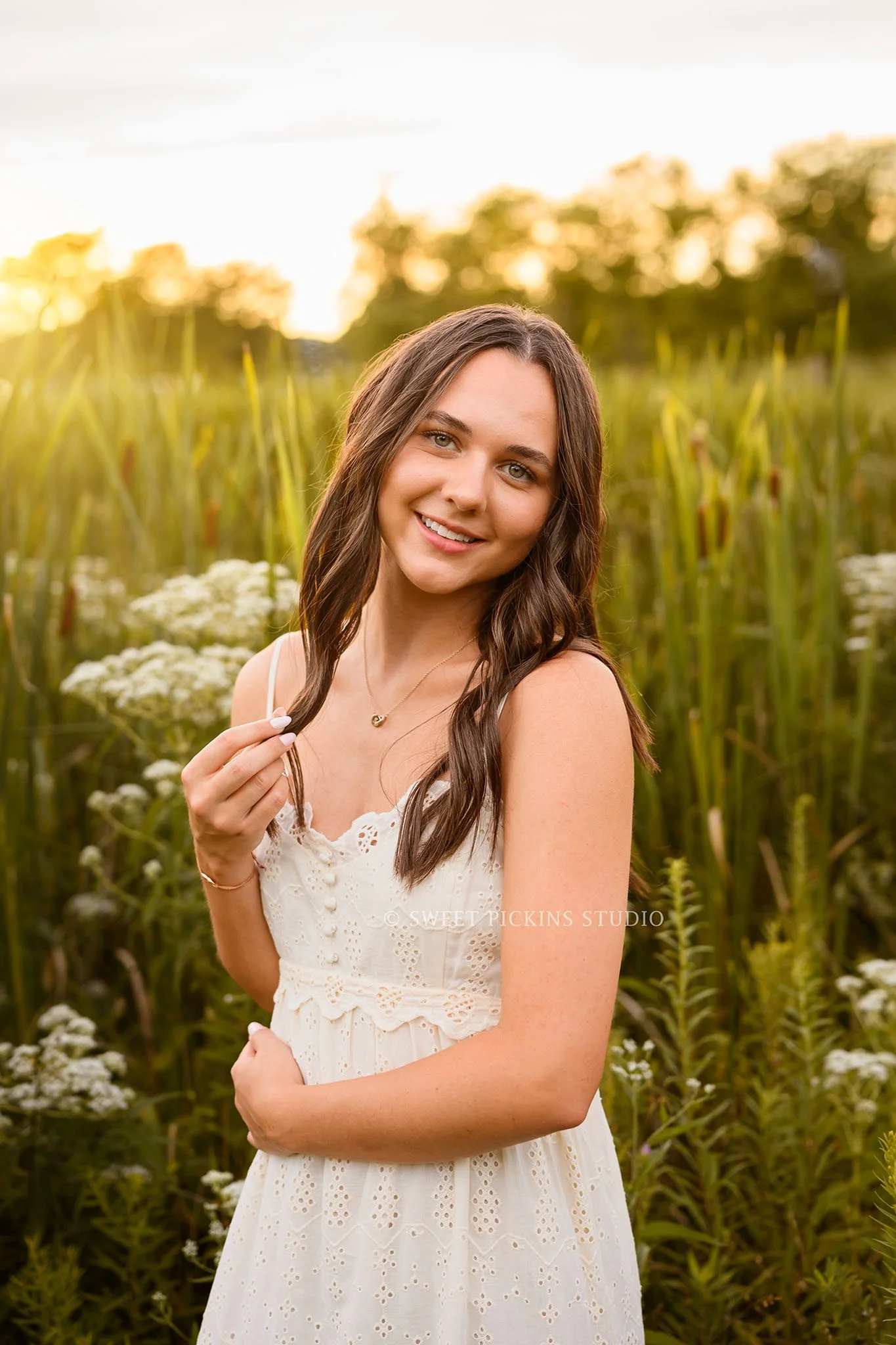 Sophie’s Carmel, Indiana Senior Photography by Sweet Pickins Studio senior photographer Amanda Wilson for class of 2027 Senior girl walking in flower field in cream maxi dress at sunset ©