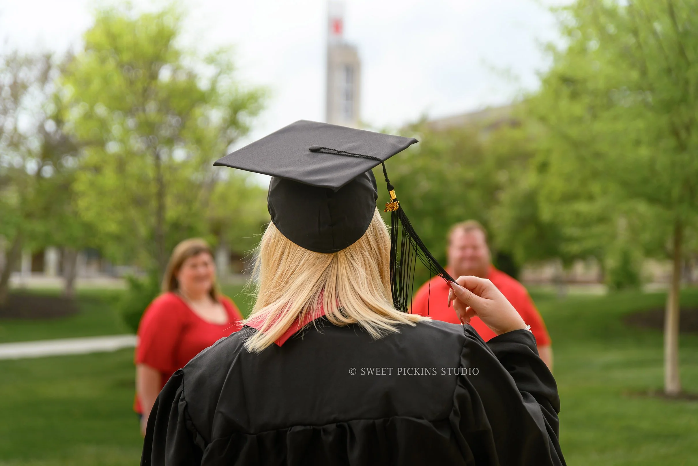 I.U. Indy Graduation Photography in Downtown Indianapolis, Indiana with class of 2026 grad wearing cap and gown with parents by Sweet Pickins Studio senior photographer Amanda Wilson ©