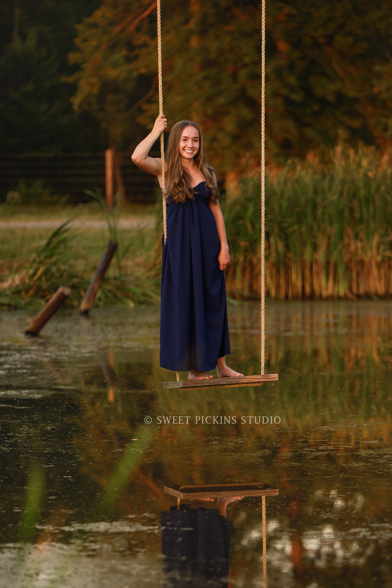 Natalie’s Lowell, Indiana Senior Photography posing on swing over pond on farm at sunset by Sweet Pickins Studio senior photographer Amanda Wilson ©