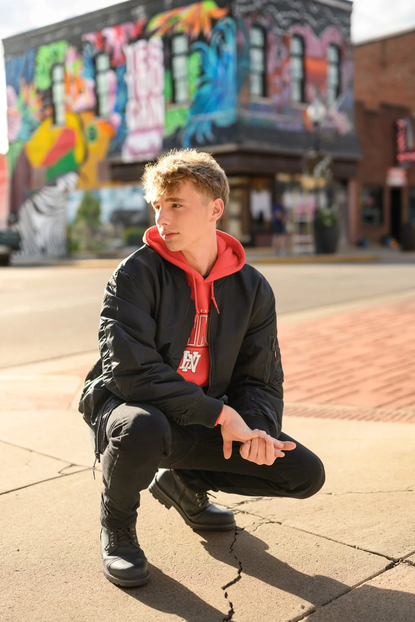 Huntington, Indiana Urban Senior Guy Photography for Huntington North Class of 2027 Senior  BOSTAN walking in urban downtown streets wearing black jacket and hoodie by Sweet Pickins Studio senior photographer Amanda Wilson ©