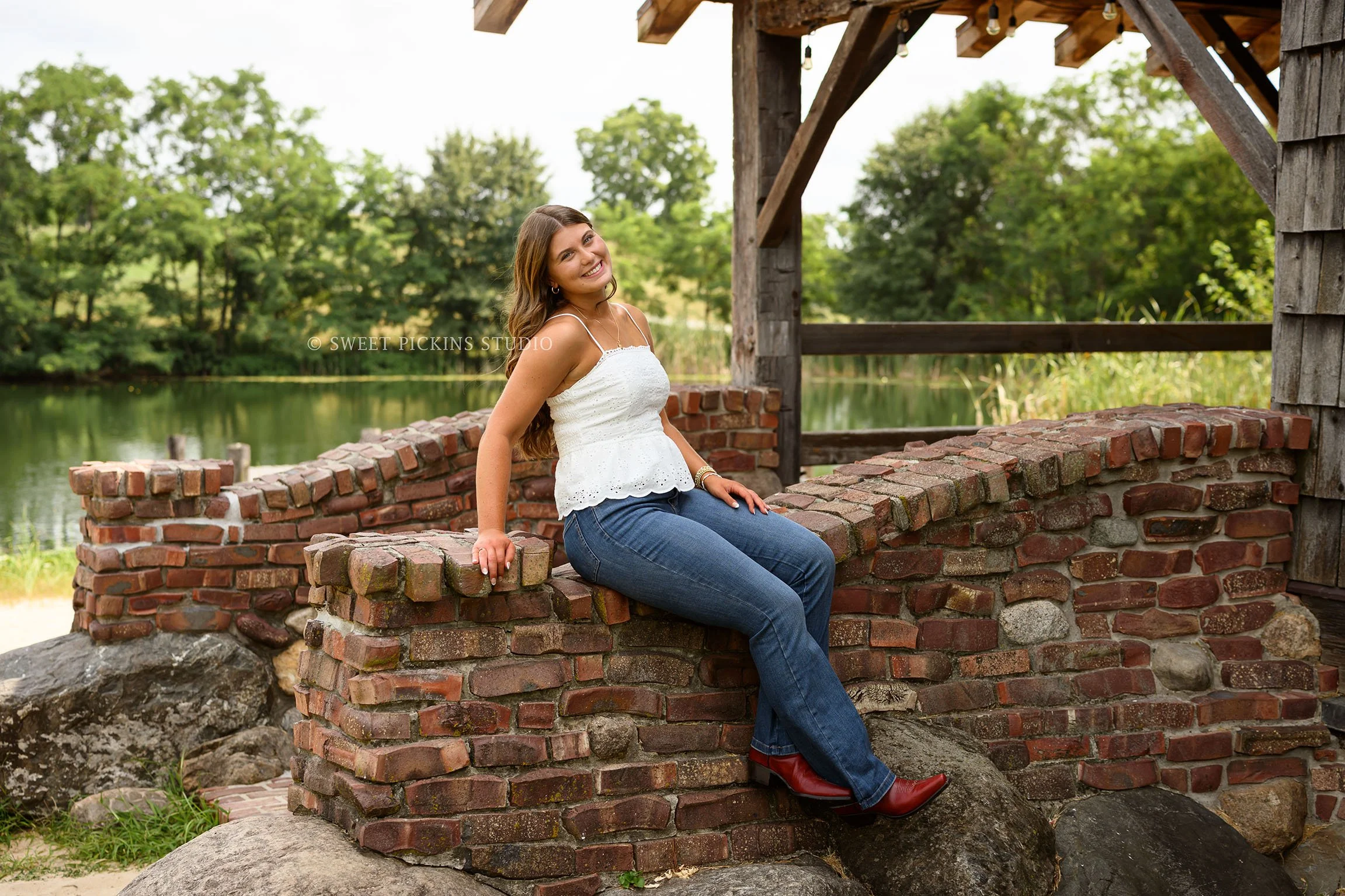Zionsville, Indiana Senior Portrait Photography at Traders Point Creamery with class of 2027 senior girl wearing denim jeans and western boots at lakeside barn by Sweet Pickins Studio senior photographer Amanda Wilson ©