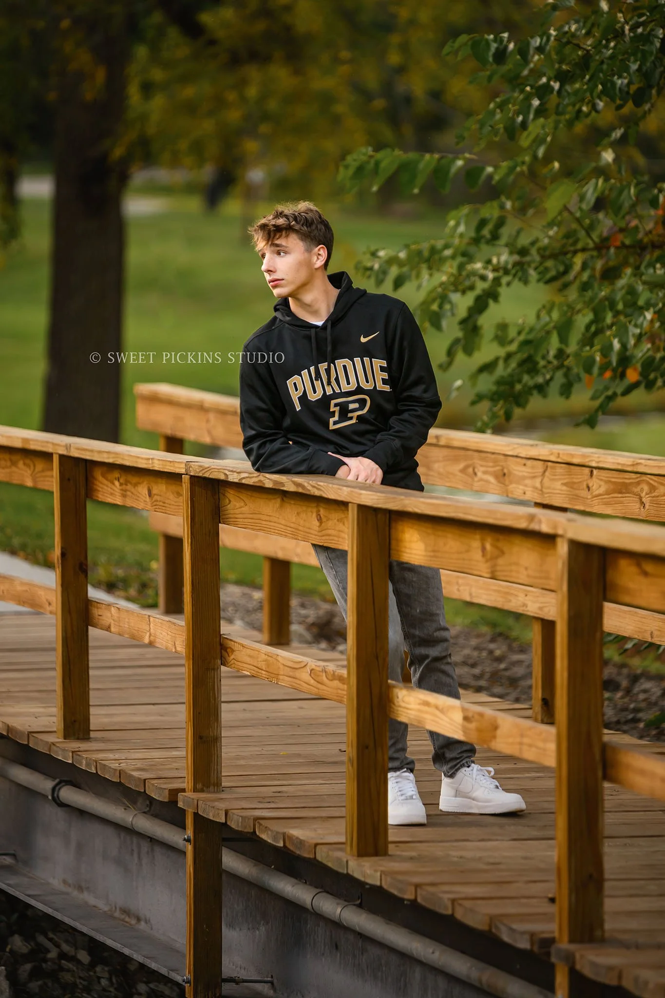 Huntington, Indiana Senior Portraits for Huntington North Class of 2027 Senior Guy BOSTAN posing in Purdue hoodie at outdoor nature park on wooden bridge in Fall by Sweet Pickins Studio senior photographer Amanda Wilson ©