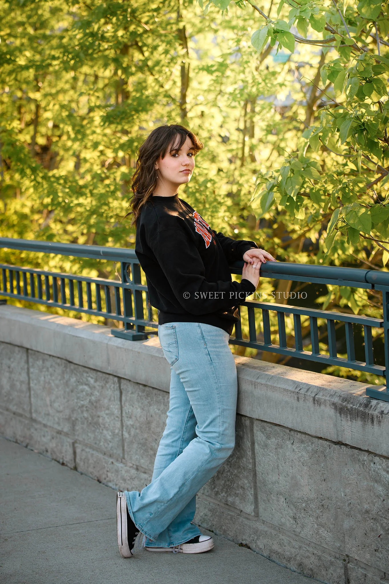 Hailee | Noblesville High School Graduation Photography in Cap and Gown at river walk wearing college sweatshirt by Sweet Pickins Studio senior photographer Amanda Wilson ©