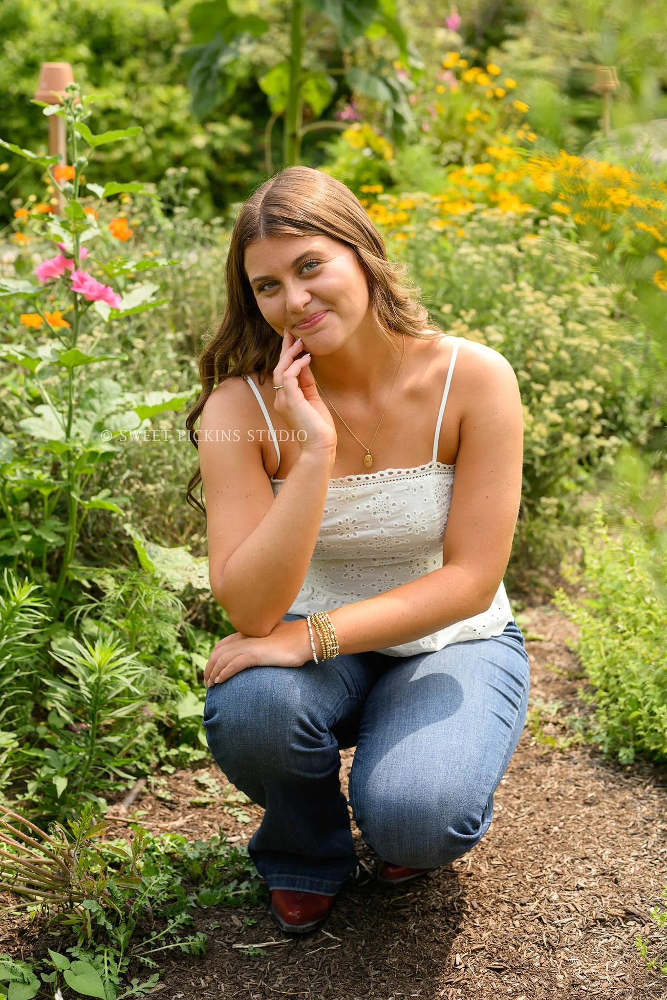 Zionsville, Indiana Floral Senior Photography at Traders Point Creamery with class of 2027 senior girl posing in jeans and red western boots in country garden by Sweet Pickins Studio senior photographer Amanda Wilson ©