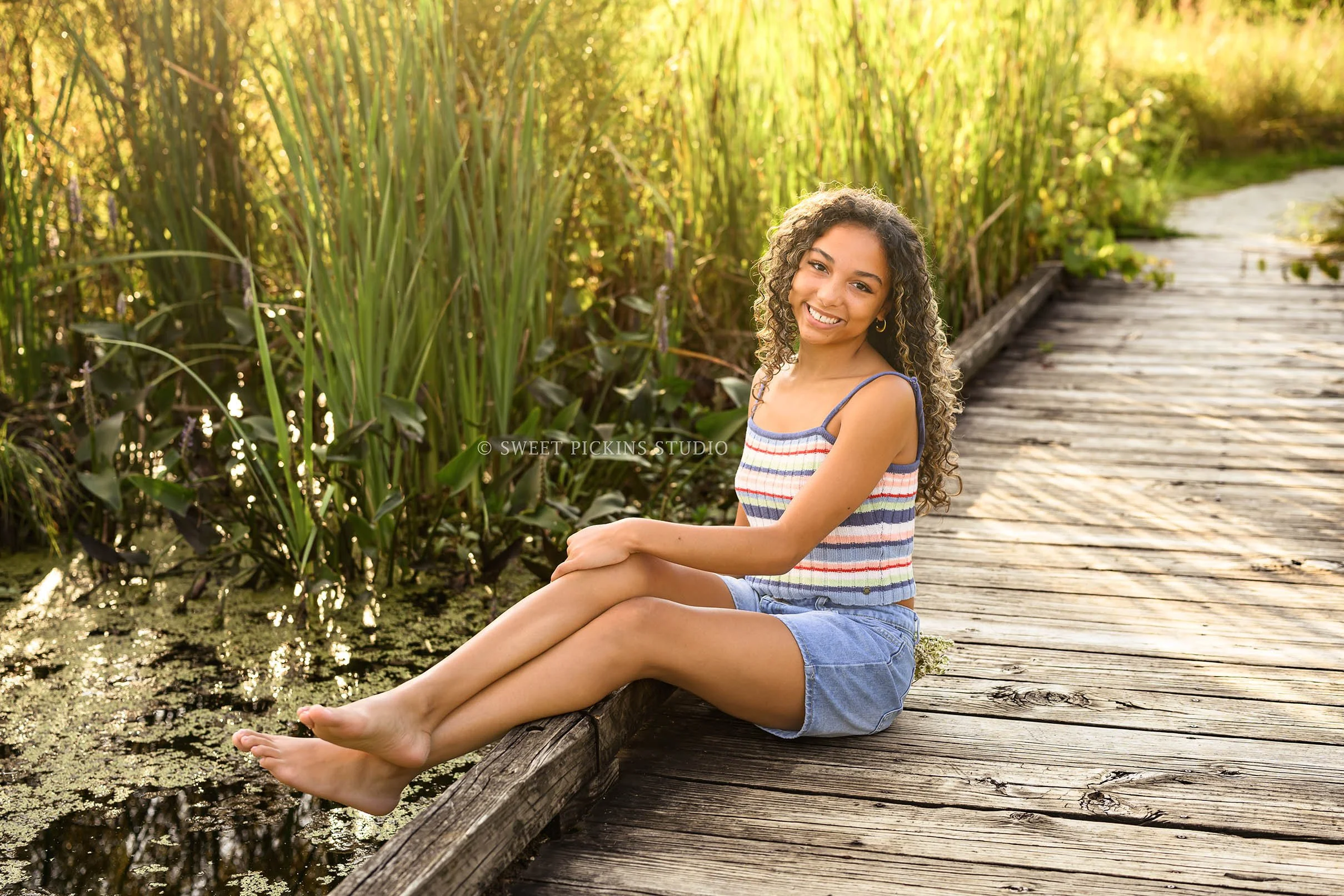 Madeline | Senior Girl Photography posing by pond for Speedway High School Class of 2027 wearing striped tank top and denim shorts by Sweet Pickins Studio senior photographer Amanda Wilson ©