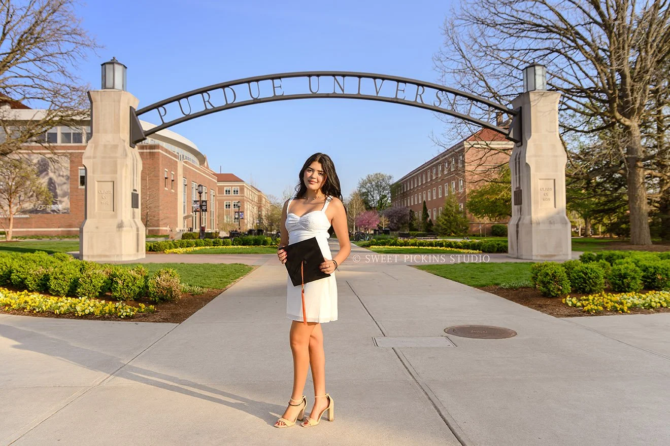 Maria’s Purdue University Graduation Pictures in West Lafayette, Indiana by Sweet Pickins Studio photographer Amanda Wilson for spring graduate posing in white dress with grad cap and tassel © 2026