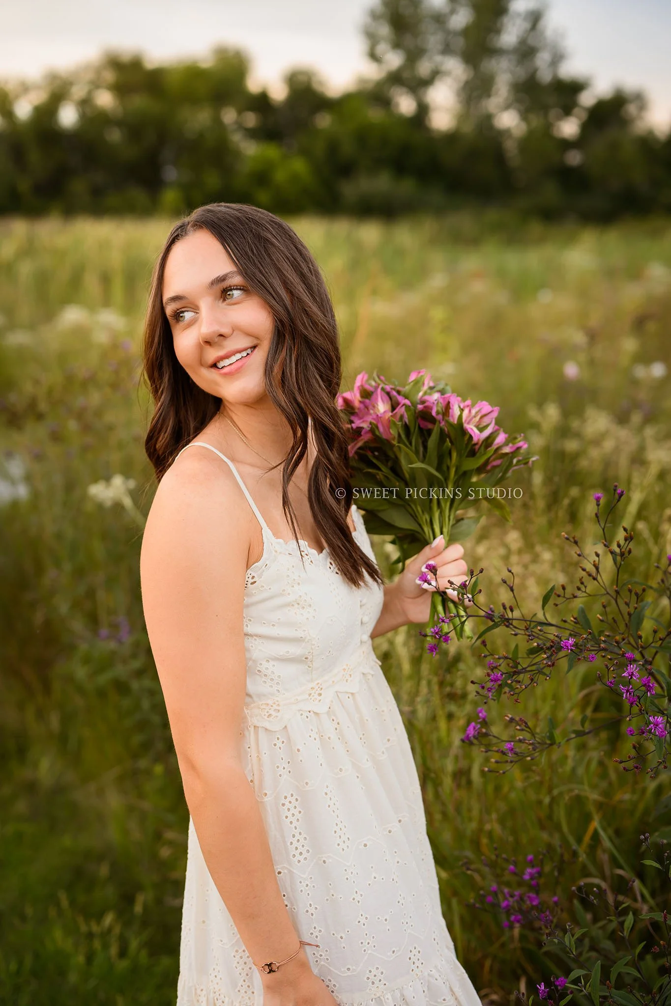 Sophie’s Carmel, Indiana Senior Photography by Sweet Pickins Studio senior photographer Amanda Wilson for class of 2027 Senior girl posing with floral bouquet in flower field in cream maxi dress at sunset ©