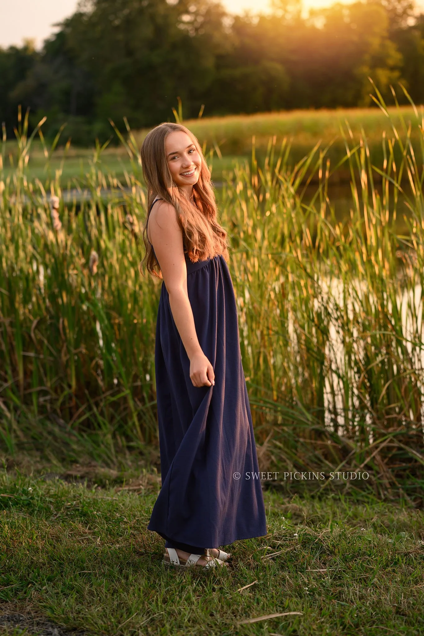 Natalie’s Lowell, Indiana Senior Photography posing in blue dress by pond at sunset on farm by Sweet Pickins Studio senior photographer Amanda Wilson ©