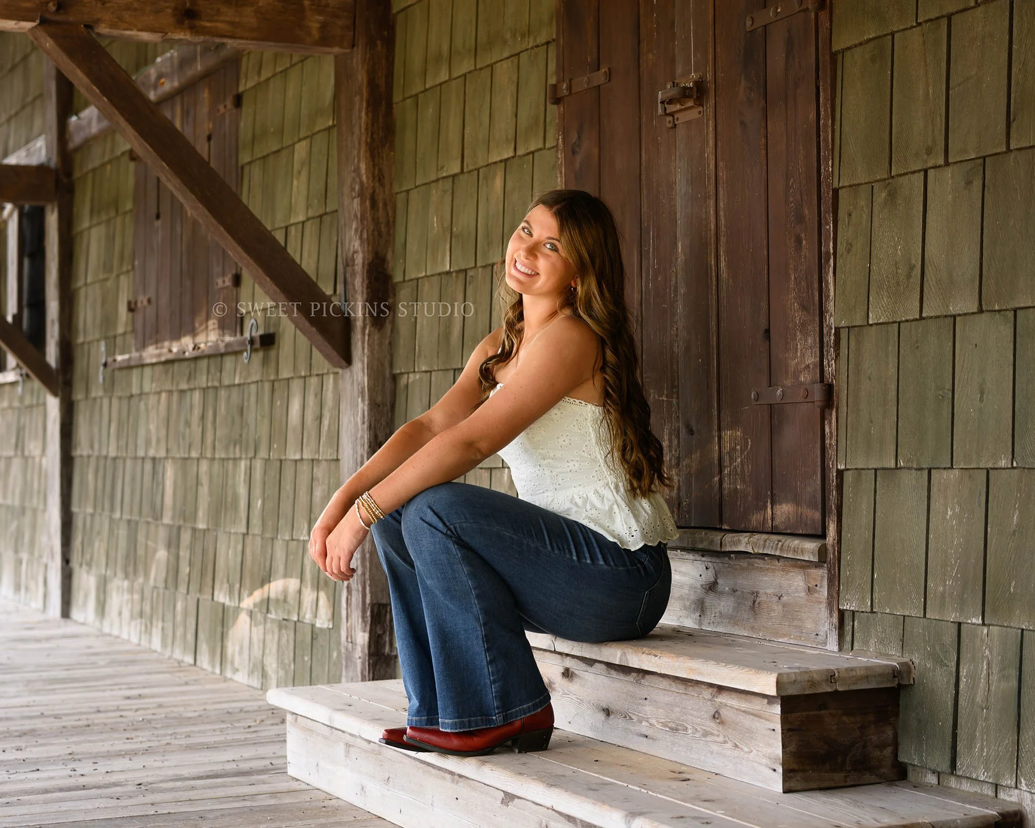 Zionsville, Indiana Country Senior Portrait Photography at Traders Point Creamery with class of 2027 senior girl wearing denim jeans and red western boots at barn by Sweet Pickins Studio senior photographer Amanda Wilson ©