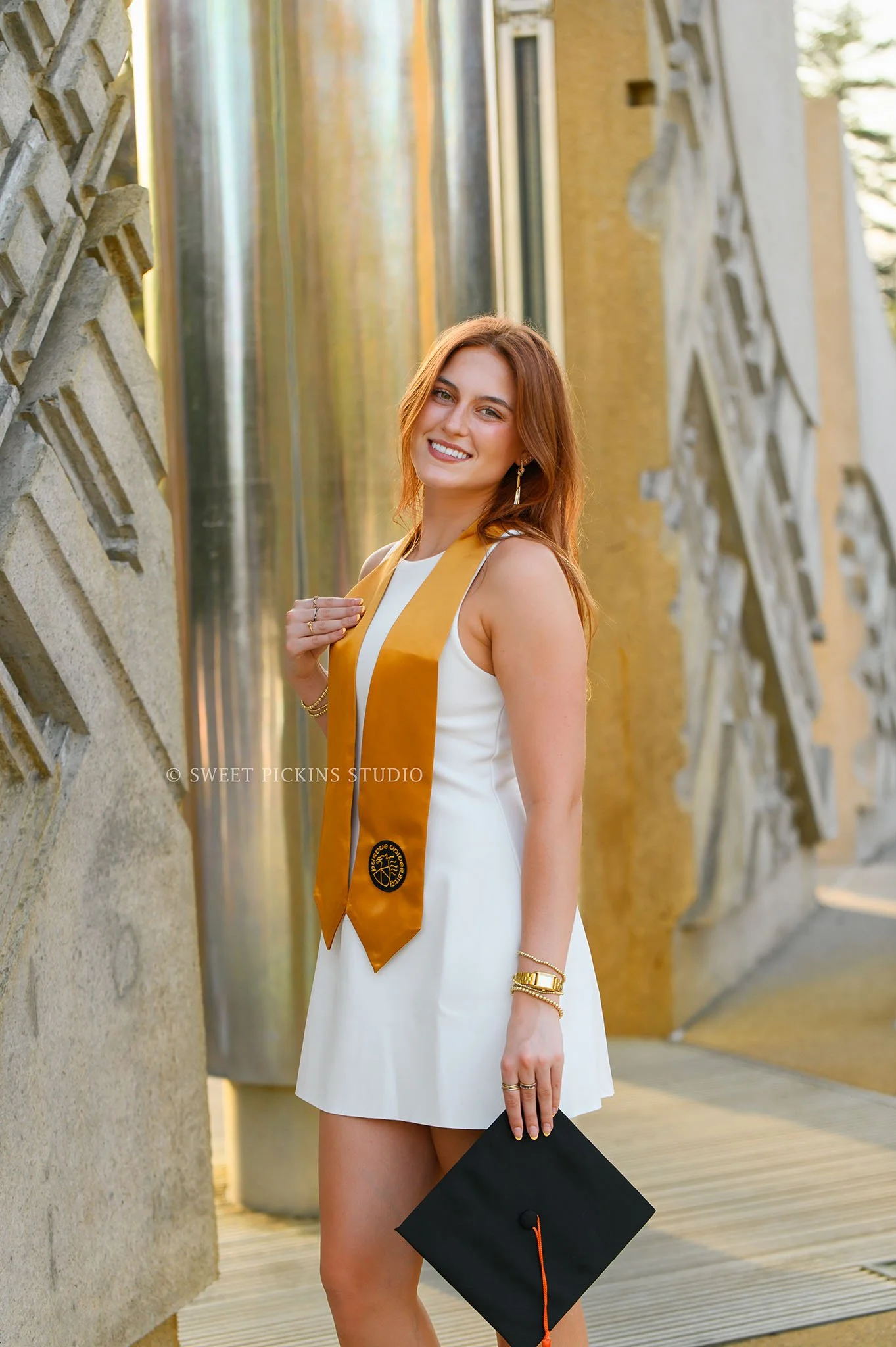 Ella’s Purdue Graduation Photography in West Lafayette, Indiana by Sweet Pickins Studio photographer Amanda Wilson for spring graduate posing in white dress at Engineering fountain with grad cap and tassel © 2026