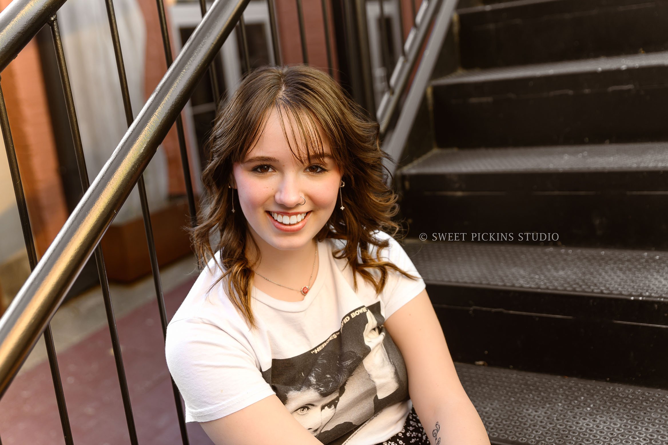 Hailee | Noblesville, Indiana Senior Portrait Photography in Urban Downtown for Noblesville High School class of 2026 senior girl posing on black stair steps in graphic tee and skirt by Sweet Pickins Studio senior photographer Amanda Wilson © 2026