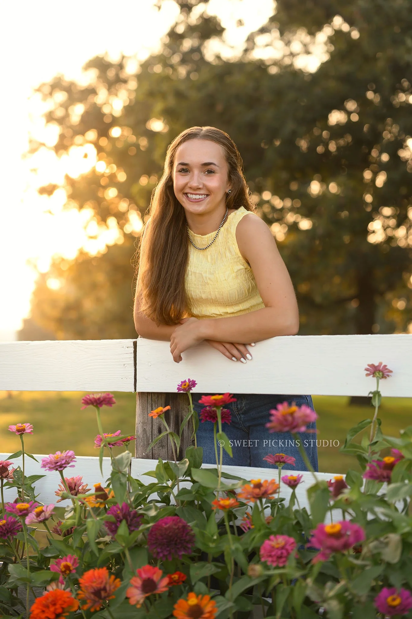 Natalie’s Lowell, Indiana Floral Senior Photography for class of 2027 senior girl posing on farm fence with colorful zinnia flowers by Sweet Pickins Studio senior photographer Amanda Wilson ©
